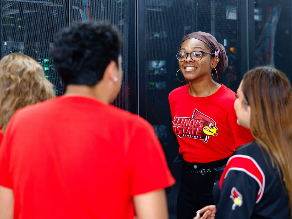 A group of students chat near server racks.