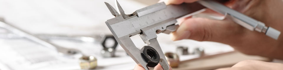 Person uses calipers to measure a nut.